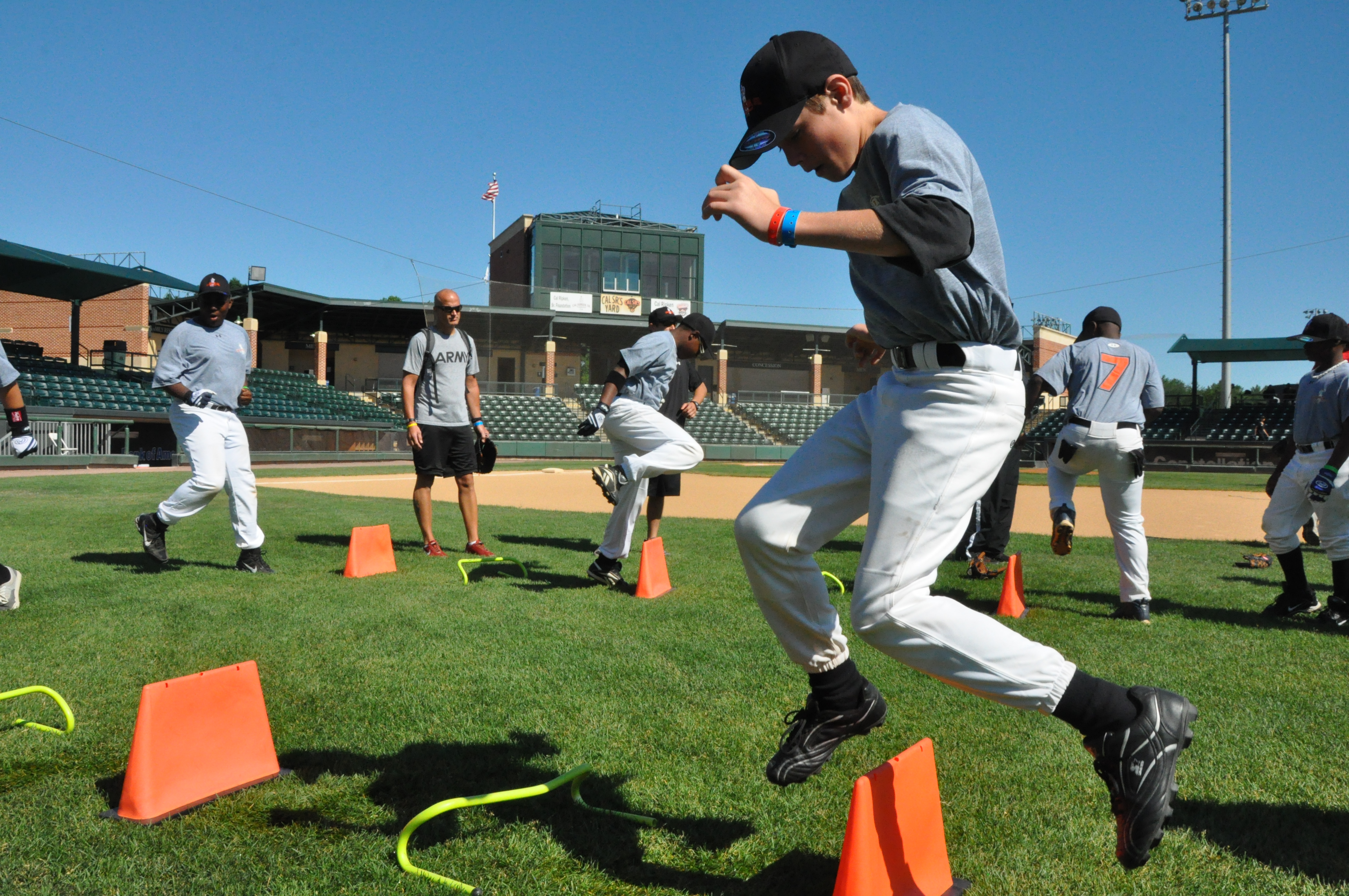 kid jumping over cones, baseball field