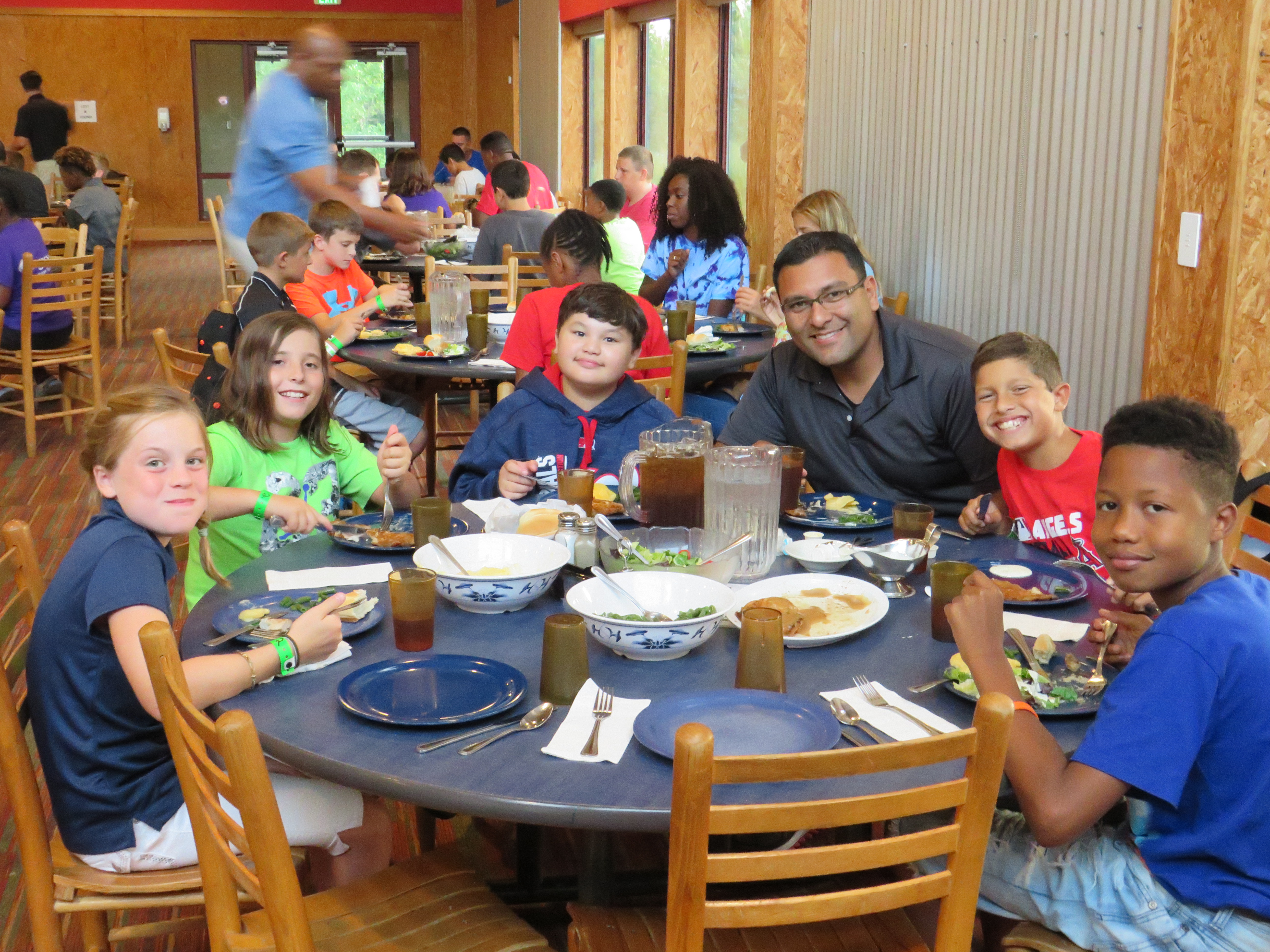 Volunteers sitting with campers during a meal