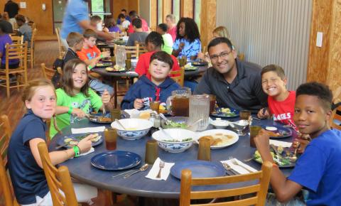 Volunteers sitting with campers during a meal
