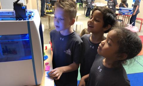 Three students observing a 3D printer in action